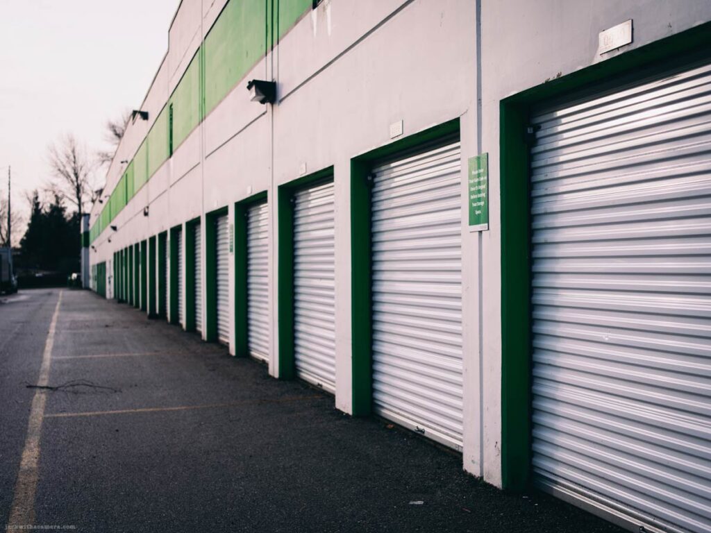 Row of closed roll-up storage doors on industrial building exterior
