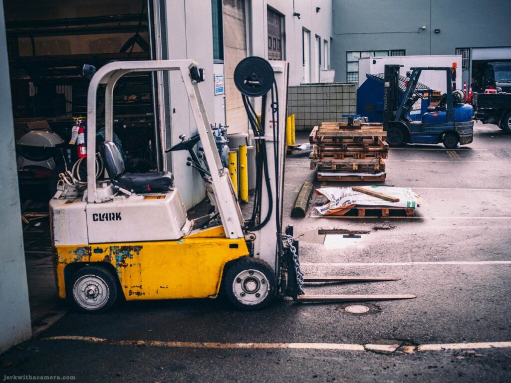 Forklift parked near pallets outside warehouse loading area
