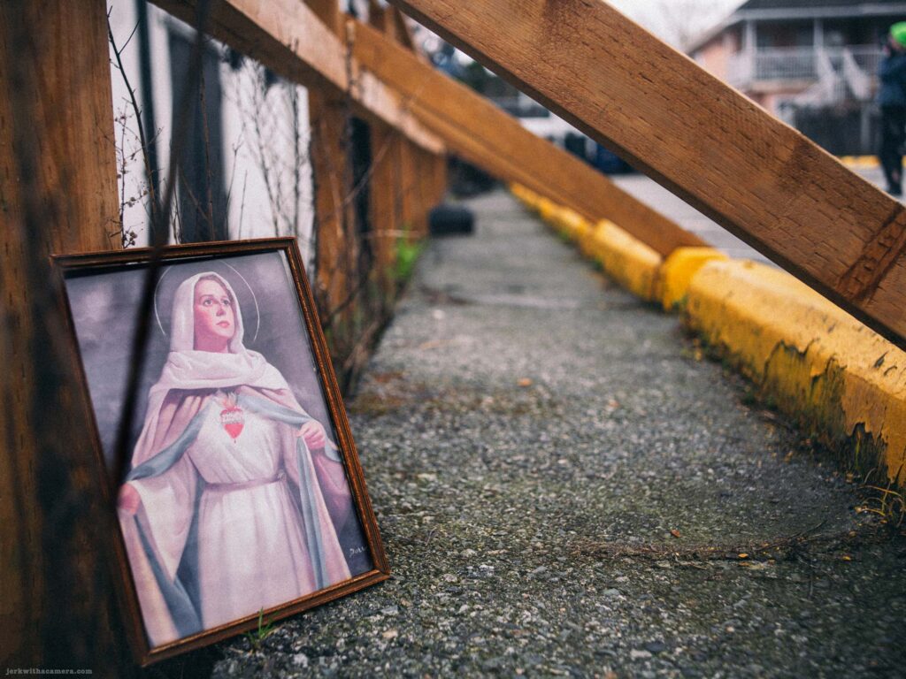 Religious portrait leaning against wooden railing beside sidewalk