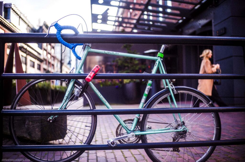 Mint green road bicycle locked behind black metal railing