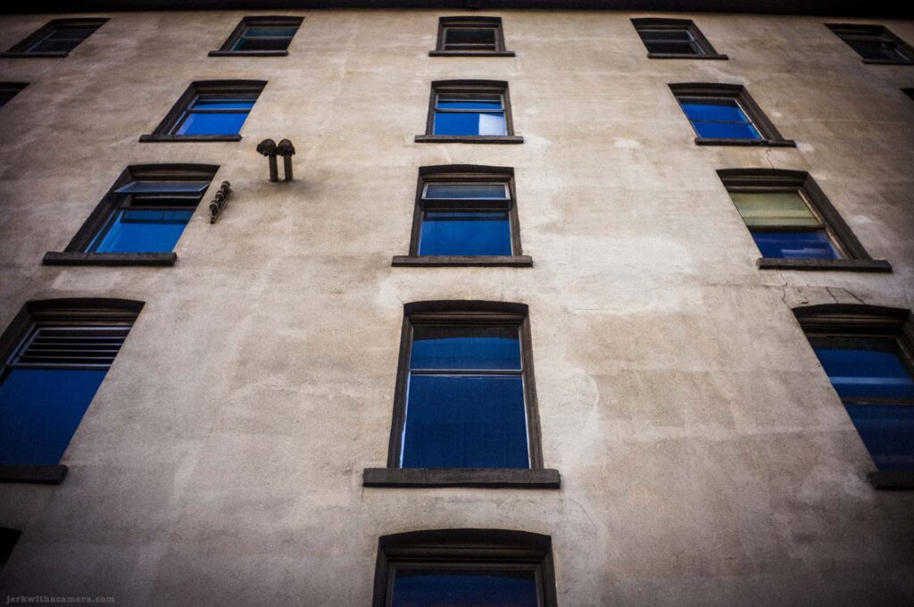 Building wall with rows of blue windows viewed from below