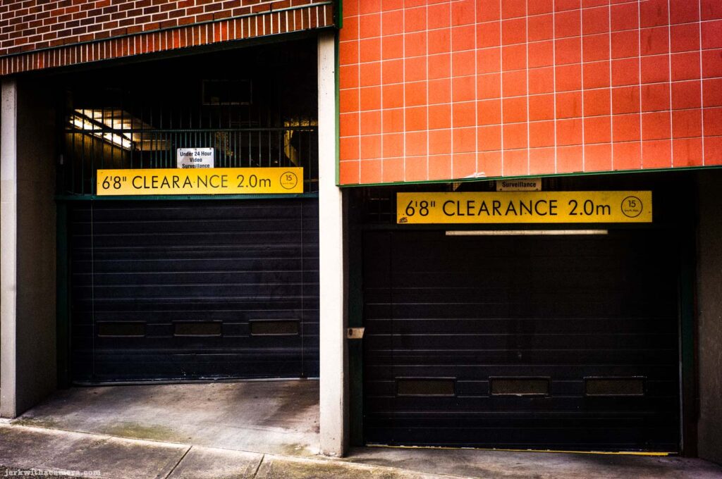 Parking garage doors with yellow clearance signs on tiled wall