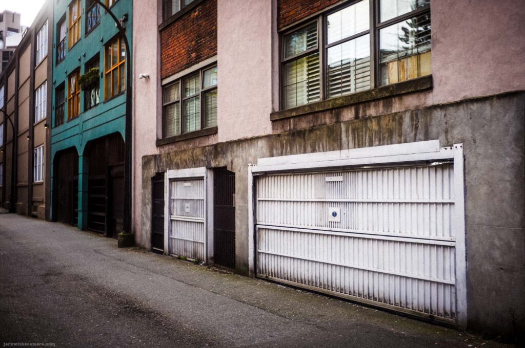 Alley with white garage doors and apartment building facades in Yaletown