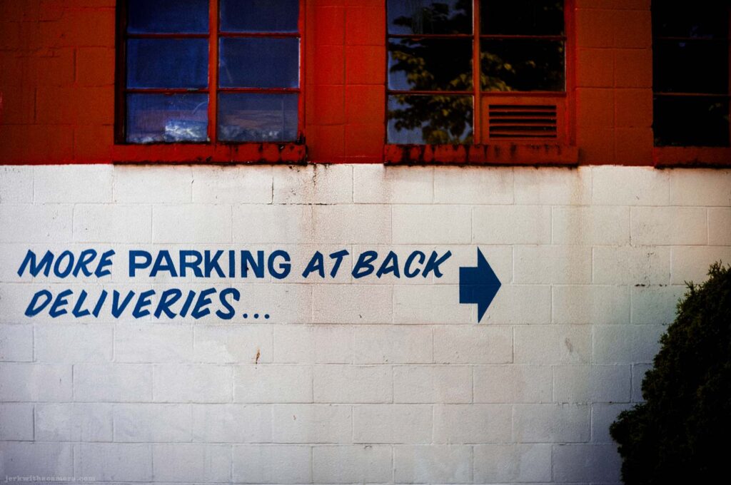 Painted parking and delivery sign on a white brick wall
