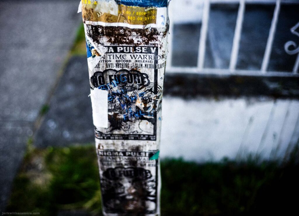 Sticker-covered utility pole with posters and torn paper
