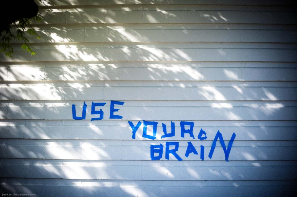 Blue painted words reading Use Your Brain on a white wall
