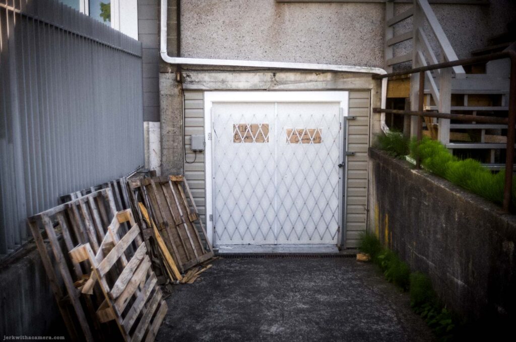 Wood pallet beside white double door and stairway on Commercial Drive in Vancouver