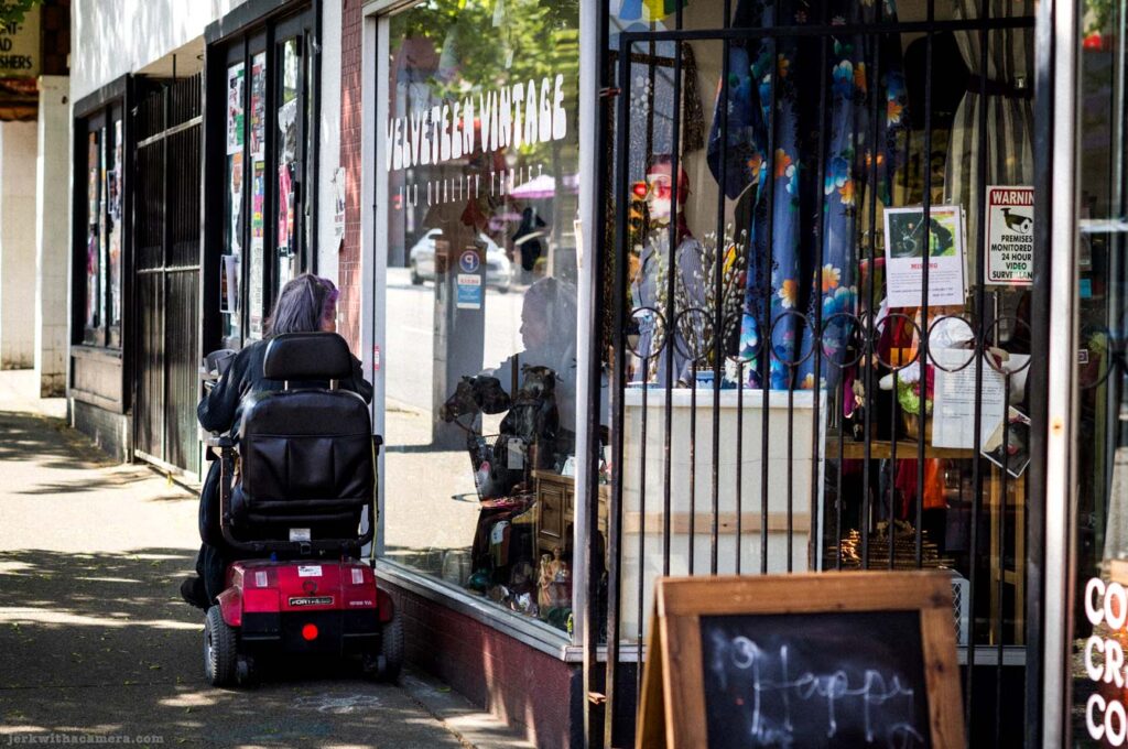 Person on a mobility scooter outside a vintage clothing store