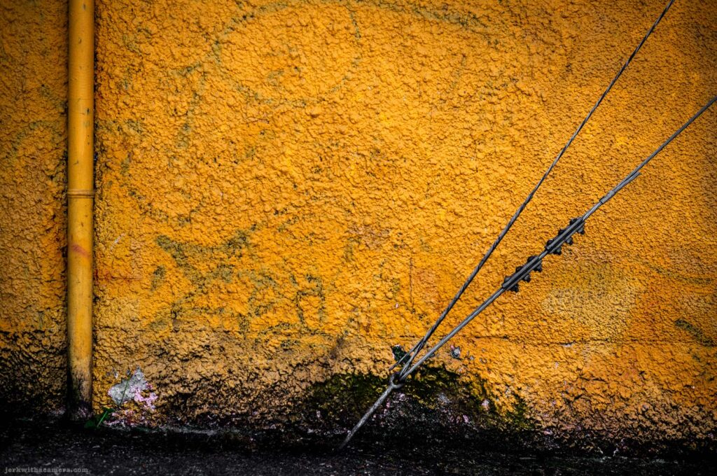 Yellow textured wall with cables running diagonally across it