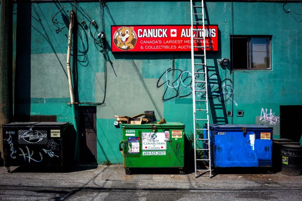 Dumpster, ladder, and auction sign on a blue-green wall