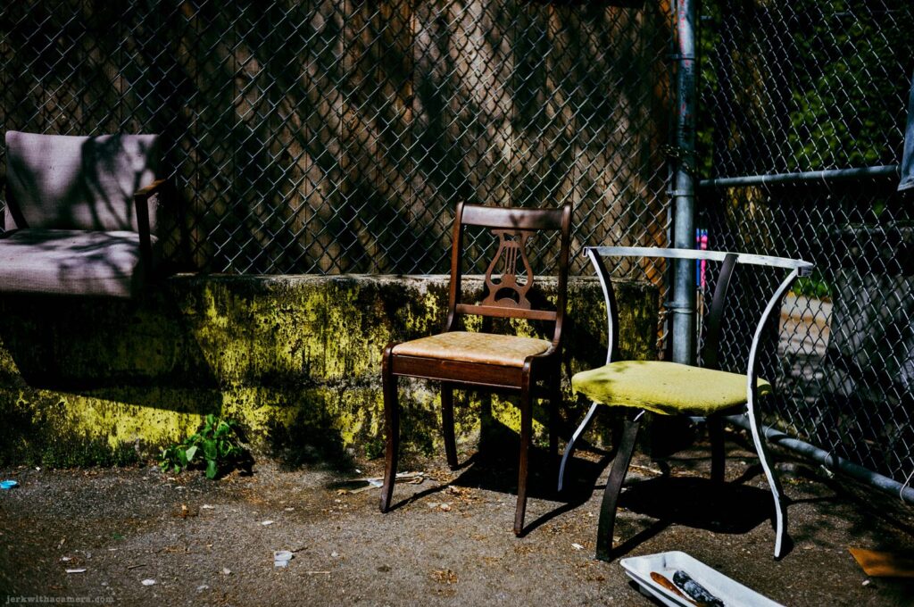 Chairs beside a chain link fence in an alley