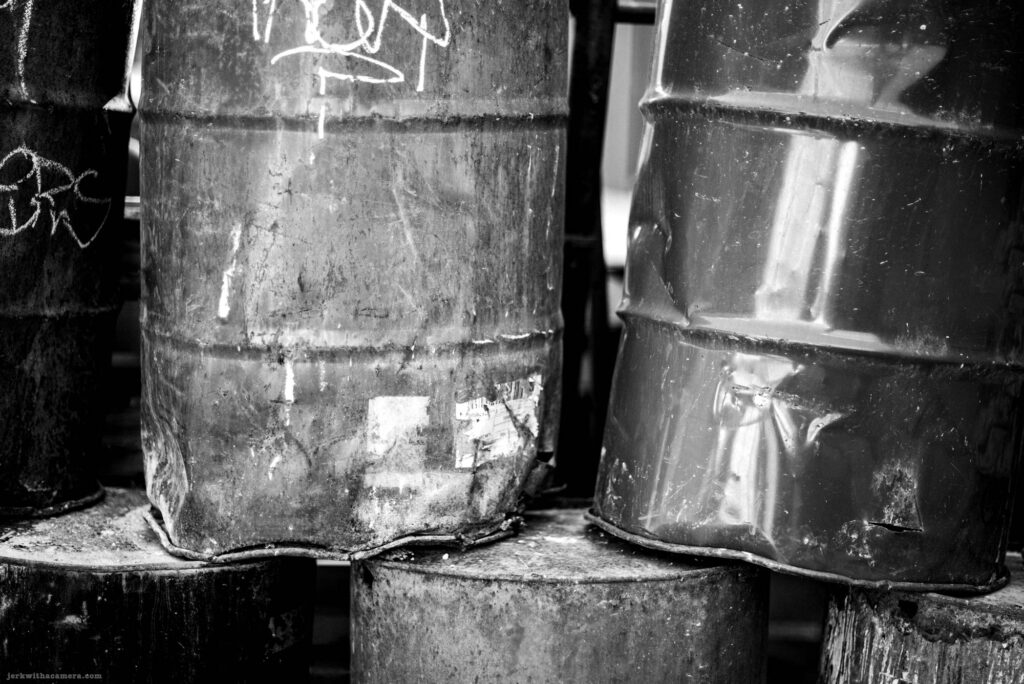 Close-up of dented metal barrels in black and white
