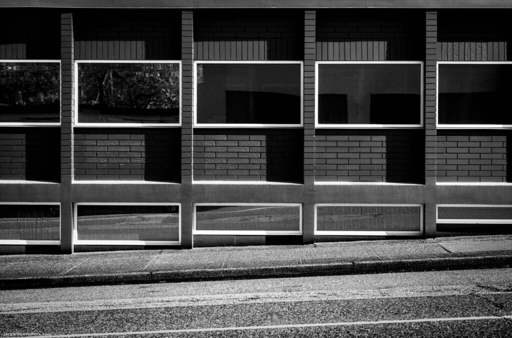 Brick wall with window grid and shadow on Commercial Drive in Vancouver