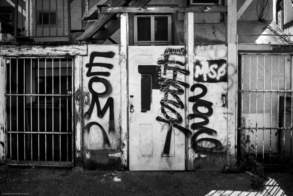 Graffiti-covered door and metal gate on Commercial Drive in Vancouver