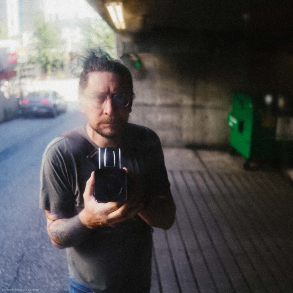 Reflection of a photographer holding a camera in a reflective surface.