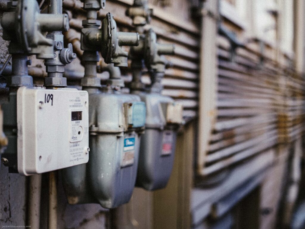 Gas meters and utility lines attached to the side of a building.
