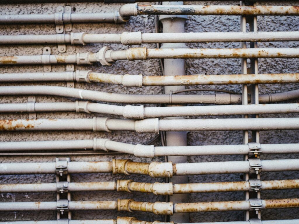 Gas meters and utility lines attached to the side of a building.