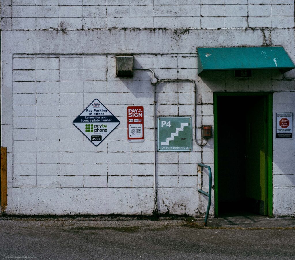 Widest view of P4 stairwell entrance on white concrete block wall with PayByPhone and Pay and Sign signs and teal awning.