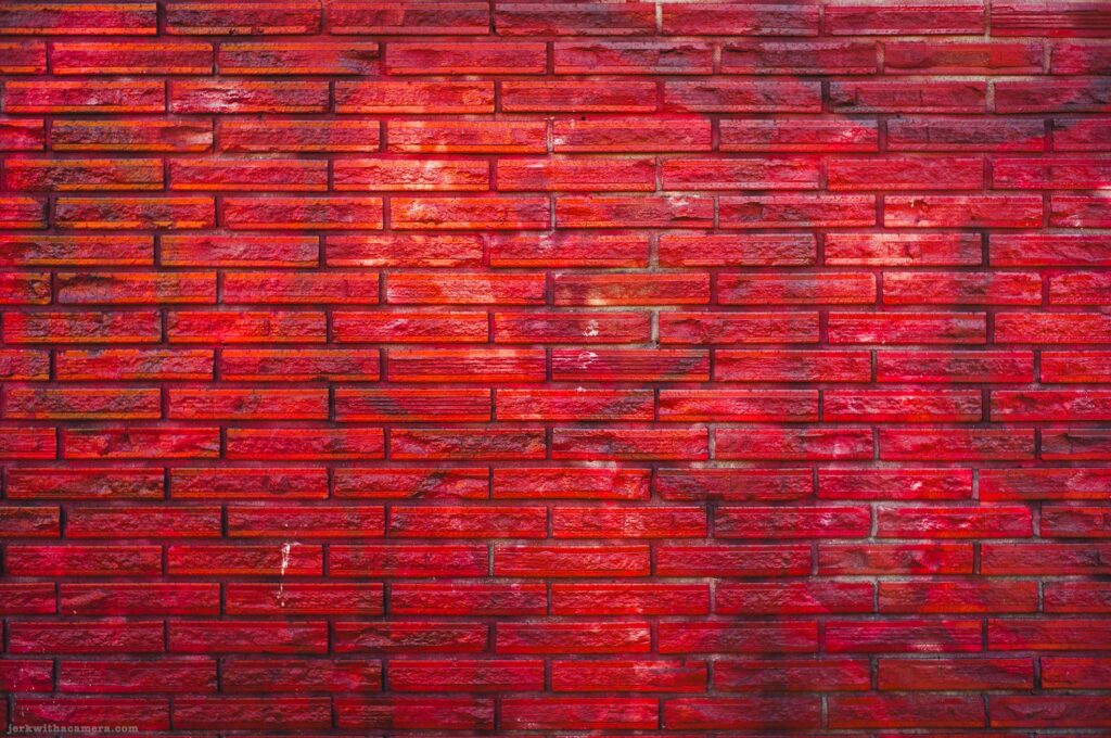 Flat face-on view of a pink painted brick wall with brighter centre. Slightly different exposure from adjacent frame.
