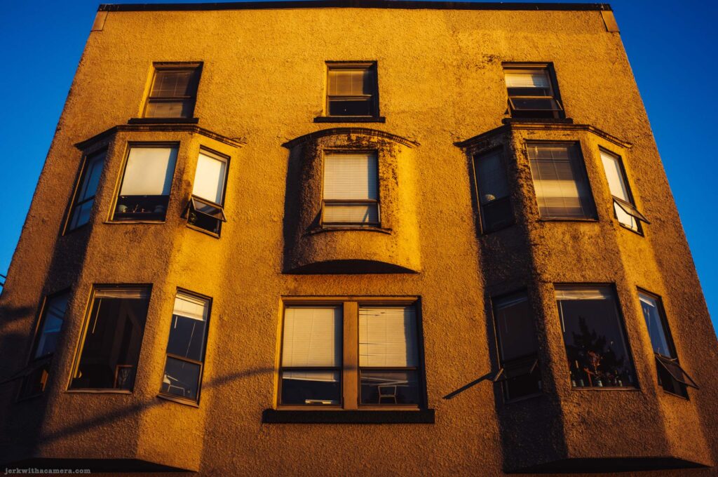 Stucco apartment building facade with bay windows. Widest of the three facade frames.