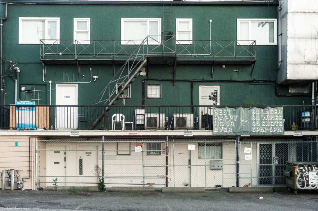 Dark green building with fire escape and Best Happy Hour Ever sign. Fourth of four frames.